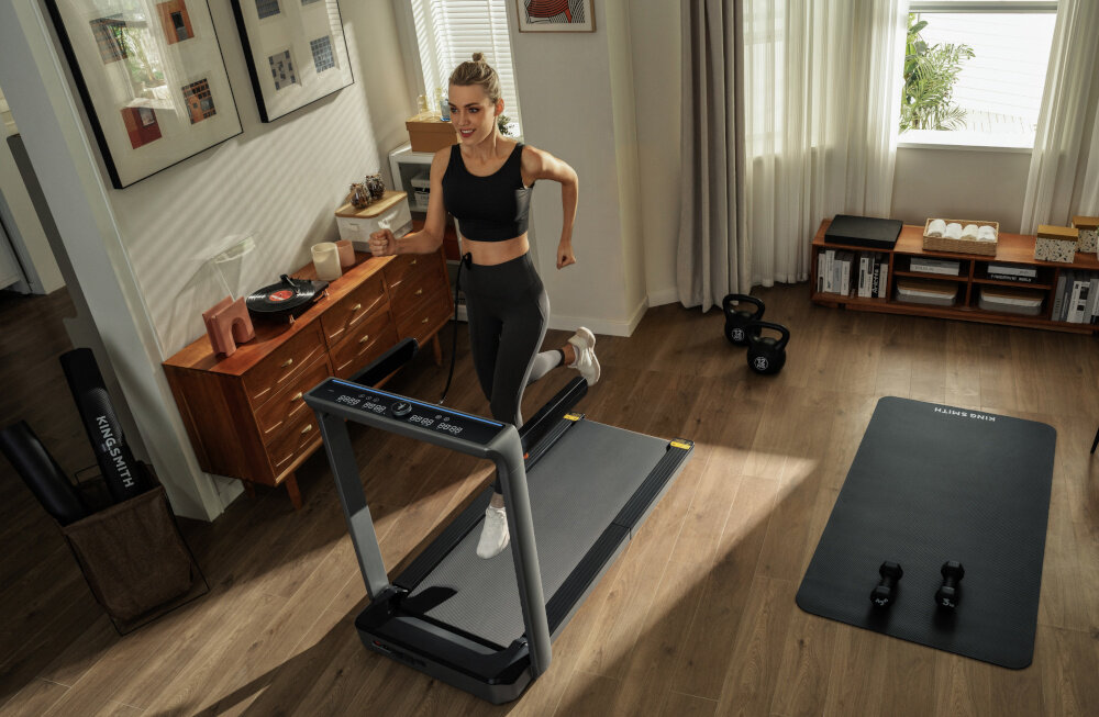 Bieżnia elektryczna KINGSMITH MX16+ Walkingpad 1470W 16km-h kobieta biegnie na bieżni czytelny panel z wyświetlaczem LED monitorowanie postępów aplikacja KS Fit sterowanie za pomocą smartfona pełna kontrola parametrów dostosowanie treningu klucz bezpieczeństwa ochrona w razie nagłego zatrzymania wykonana ze stopu aluminium