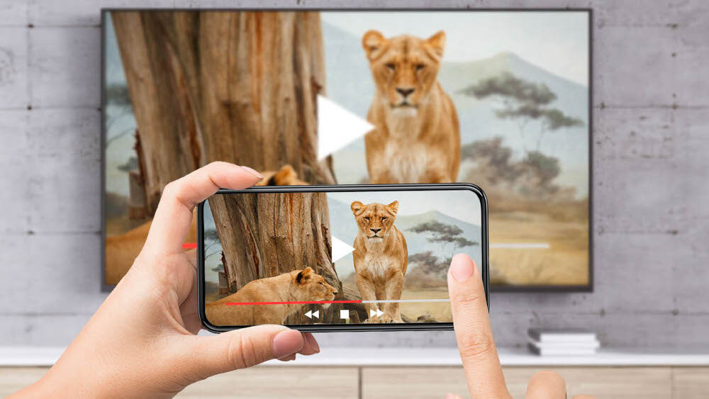 Odtwarzacz multimedialny 4K TESLA MediaBox XA400 Android TV dostęp do aplikacji bez wymiany sprzętu, telewizor zawieszony na ścianie, ręce trzymające smartfona