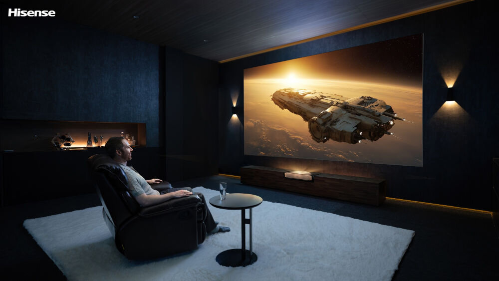 Laser TV HISENSE 100L9QD projekcja do 200 cali ekran ALR kino domowe, osoba siedząca w fotelu oglądająca film