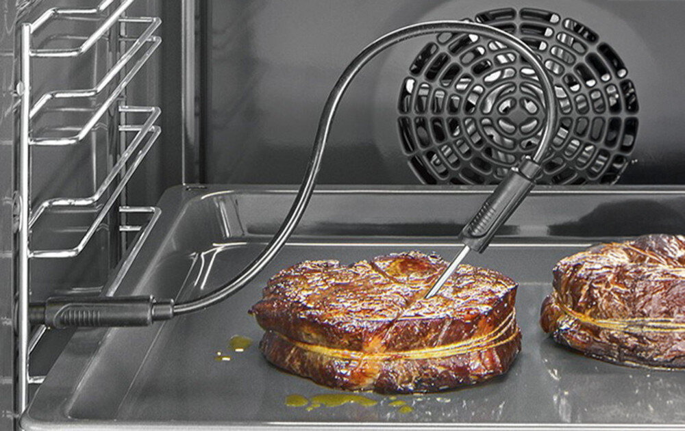 PIEKARNIK BOSCH HBG7242BB1 W środku piekarnika znajdują się dwa kawałki mięsa, a w jeden z nich wbita jest sonda temperatury połączona przewodem z gniazdem wewnątrz komory. Ujęcie podkreśla kontrolę temperatury potrawy podczas pieczenia Termosonda kontrola temperatury