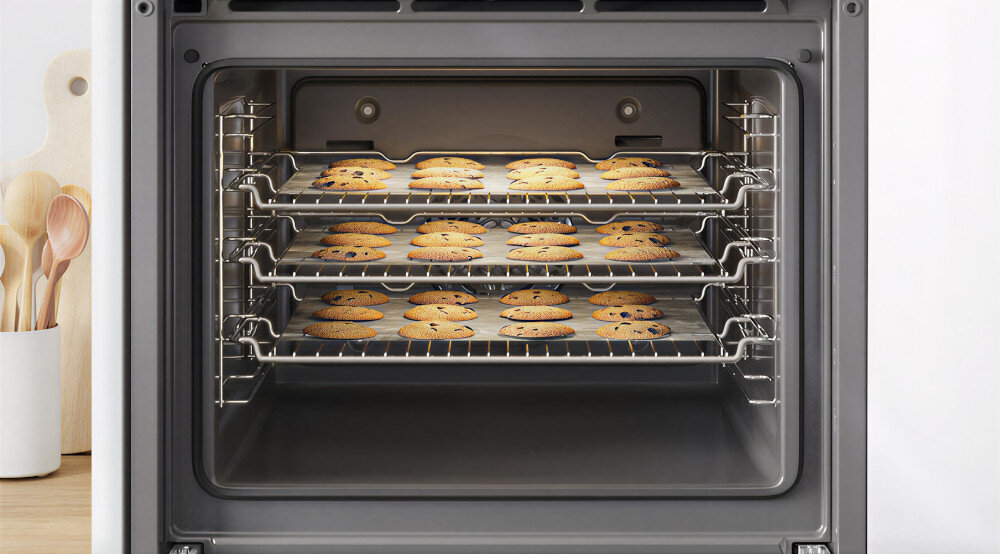 PIEKARNIK BOSCH HBG7242BB1 Wnętrze piekarnika mieści trzy poziomy krat, na których równomiernie ułożono blachy z upieczonymi ciastkami. Ujęcie pokazuje dużą pojemność komory i możliwość pieczenia kilku partii jednocześnie Termoobieg 3D równomierne pieczenie na wielu poziomach