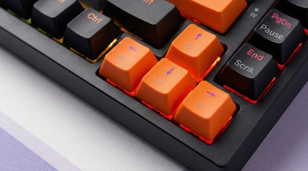 Fragment klawiatury z pomarańczowymi i czarnymi klawiszami, z widocznymi napisami takimi jak \'Ctrl\', \'PgDn\', \'Pause\', \'End\', \'Scrlk\'. Klawisze mają podświetlenie w kolorze czerwonym.