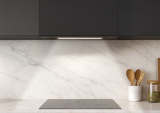 Okap MPM-54-OWS-01 w zabudowie kuchennej nad płytą indukcyjną. Włączona lista z oświetleniem LED.