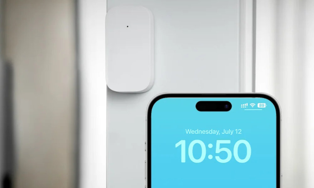 AQARA DW-S03D element systemu alarmowego trybu ochronnego sygnalizację w hubie powiadomienie na smartfon - czujnik na futrynie, z przodu widać smartfon