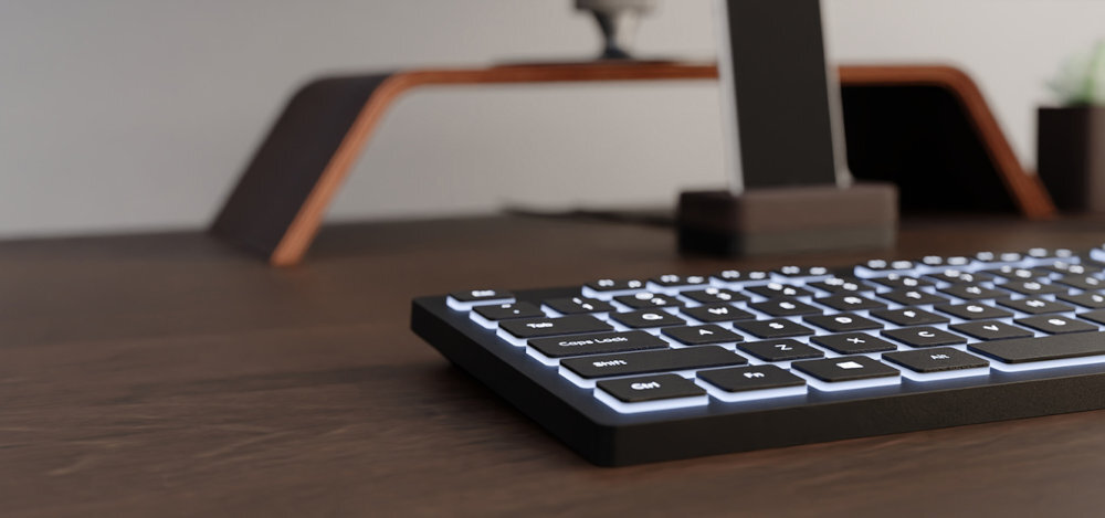 Klawiatura NATEC Herring Glow Subtelne białe podświetlenie ułatwia pracę po zmroku oraz w warunkach słabego oświetlenia równomiernemu podświetleniu klawiszy - klawiatura na drewnianym blacie z bliska