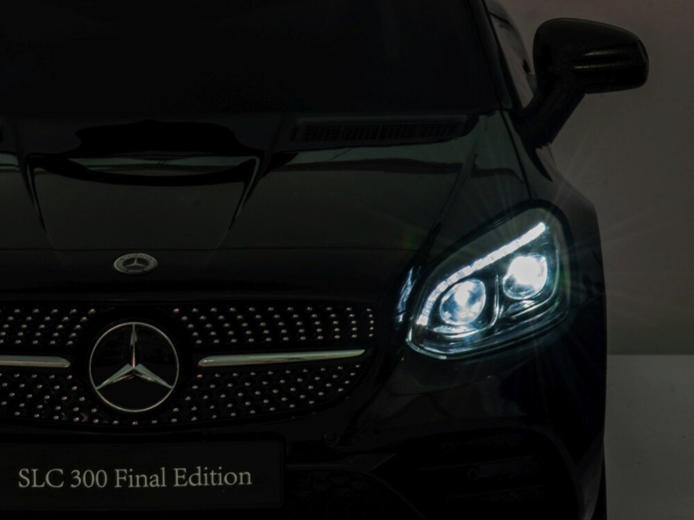 Samochód dla dziecka MILLY MALLY Mercedes-Benz SLC Czarny ciemne tło zbliżenie na przód włączone przednie światło otwierane drzwi lusterka boczne światła LED z przodu bardzo realistyczne wrażenia certyfikaty bezpieczeństwa CE i EN71 wysoka jakość wykonania zgodność z obowiązującymi normami