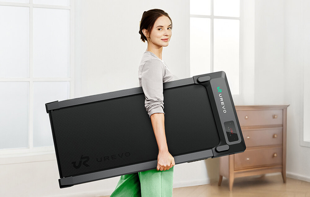 Bieżnia elektryczna UREVO Spacewalk E1L 1865W 6.4 km-h pokój osoba trzyma bieżnię pod pachą aplikacja UREVO APP przygotowuje szczegółowe podsumowania wirtualne mapy różnorodne tryby ćwiczeń