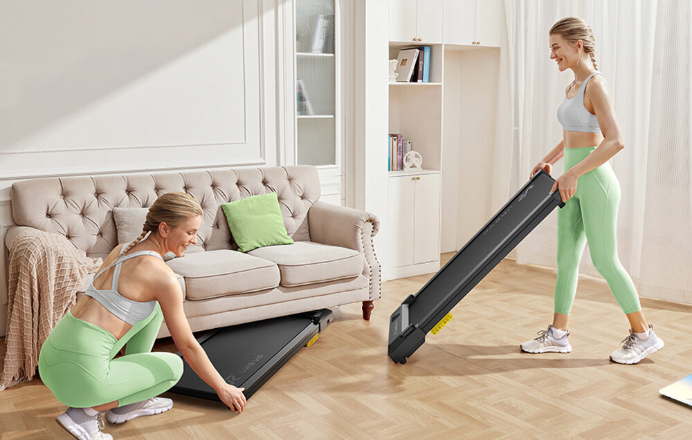 Bieżnia elektryczna UREVO Spacewalk E1L 1865W 6.4 km-h pokój dwa ujęcia osoba chowa bieżnię pod kanapą drugie ujęcie osoba przesuwa bieżnię na rolkach transportowych silnik o mocy 2,5 HP pracuje stabilnie generuje hałas poniżej 45 dB dwustopniowy system amortyzacji dwie miękkie poduszki osiem silikonowych amortyzatorów 5-warstwowy pas antypoślizgowy wzmocniona konstrukcja obciążenie do 181 kg waga około 16,6 kg wymiary 107 × 48 × 10,5 cm