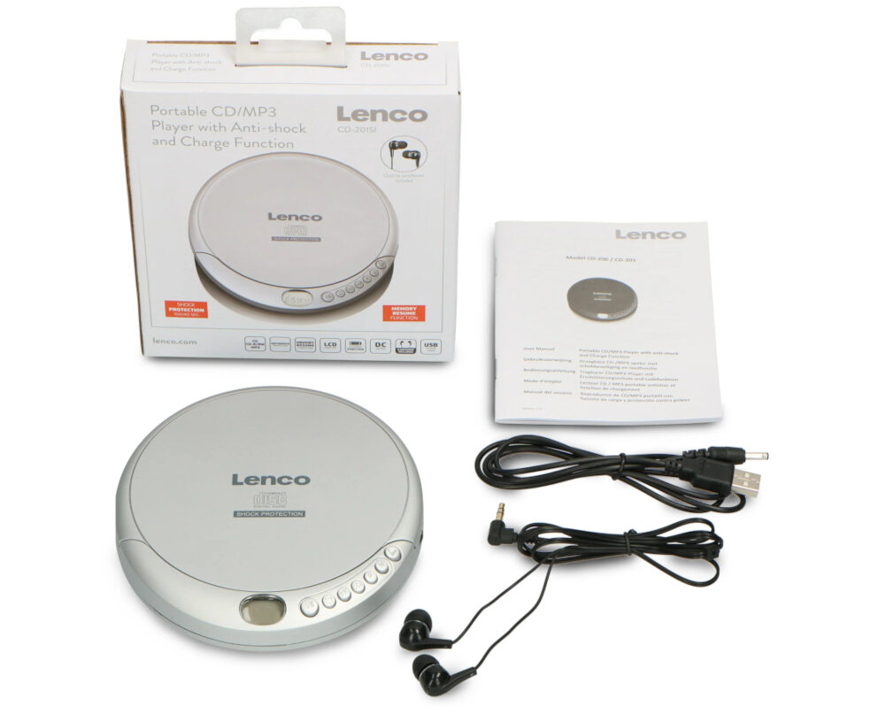 Na obrazie znajduje się srebrny odtwarzacz CD marki Lenco z widocznym logo, obok niego leży instrukcja obsługi oraz zestaw słuchawkowy i kabel USB. W tle widoczne jest opakowanie produktu z napisem \'Portable CD/MP3 Player with Anti-shock and Charge Function\'.