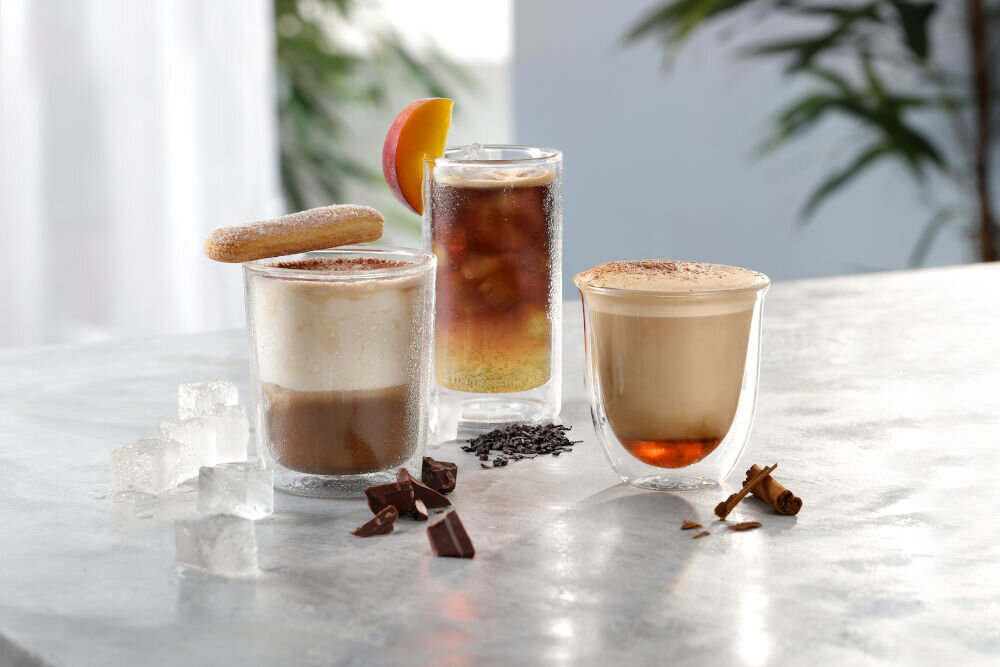 Kreatywne napoje kawowe z ekspresu De'Longhi: kawa mrożona z brzoskwinią, deser kawowy z biszkoptem oraz kawa z cynamonem i czekoladą.