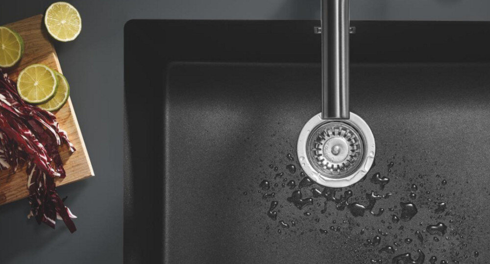 Zlewozmywak dwukomorowy GROHE K700 90-C 83.8/55.9 2.0 31657AP0 Zlew pokazany z góry z kroplami wody wokół odpływu. Obok leżą kawałki limonki i warzyw cichy zlewozmywak GROHE Whisper redukcja hałasu komfort