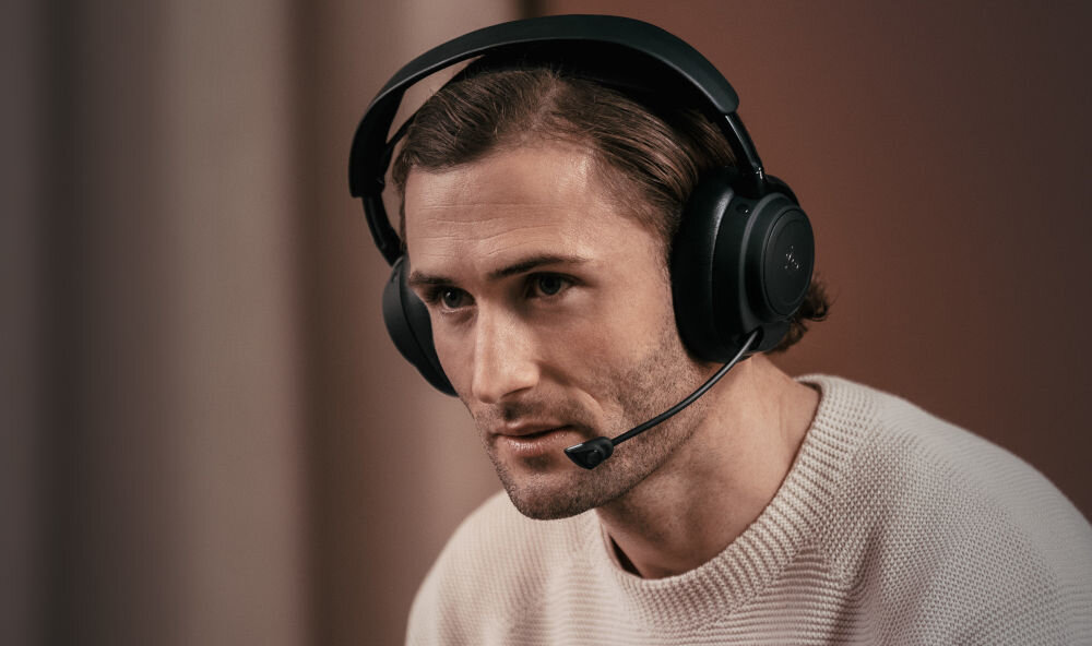 Słuchawki STEELSERIES Arctis Nova Elite włókno węglowe pasmo 10Hz-40kHz, osoba z założonymi słuchawkami nausznymi z mikrofonem