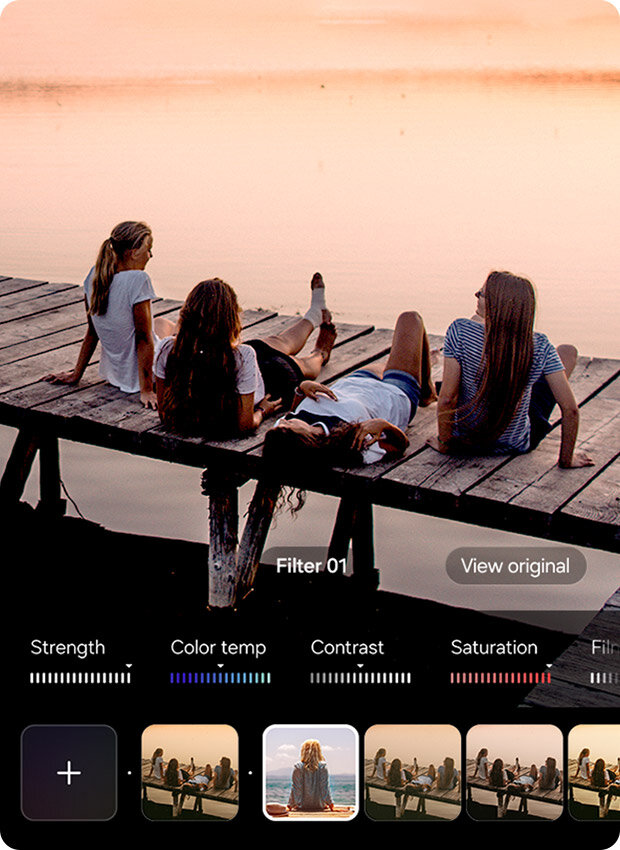 Cztery osoby siedzą na drewnianym pomoście nad wodą o zachodzie słońca. Na dole widoczny jest interfejs edycji z suwakami do regulacji intensywności, temperatury barw, kontrastu i nasycenia, a także opcjami filtrów, z których jeden jest wybierany w centrum. Cztery osoby siedzą na drewnianym pomoście nad wodą o zachodzie słońca. Na dole widoczny jest interfejs edycji z suwakami do regulacji intensywności, temperatury barw, kontrastu i nasycenia, a także opcjami filtrów, z których jeden jest wybierany w centrum.