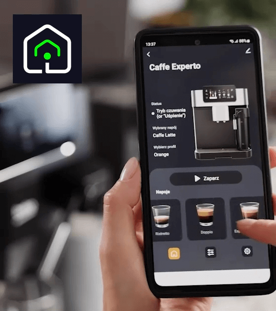 Osoba trzyma smartfon z aplikacją do obsługi ekspresu do kawy, na ekranie widoczny jest model ekspresu i opcje wyboru napojów. W lewym górnym rogu znajduje się logo z symbolem domu.