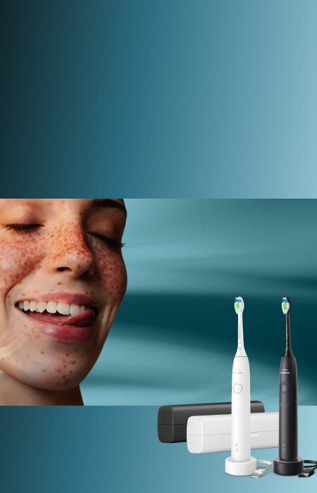 Zbliżenie na twarz uśmiechniętej kobiety, która językiem przesuwa po zębach. Obok zestaw szczoteczek sonicznych z etui.