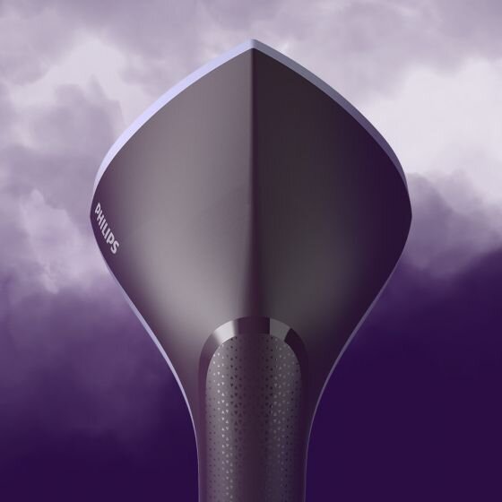 Zdjęcie przedstawia zbliżenie na końcówkę parownicy do ubrań w kolorze ciemnym, z widocznym logo \'PHILIPS\'. Tło jest fioletowe z efektem chmur.