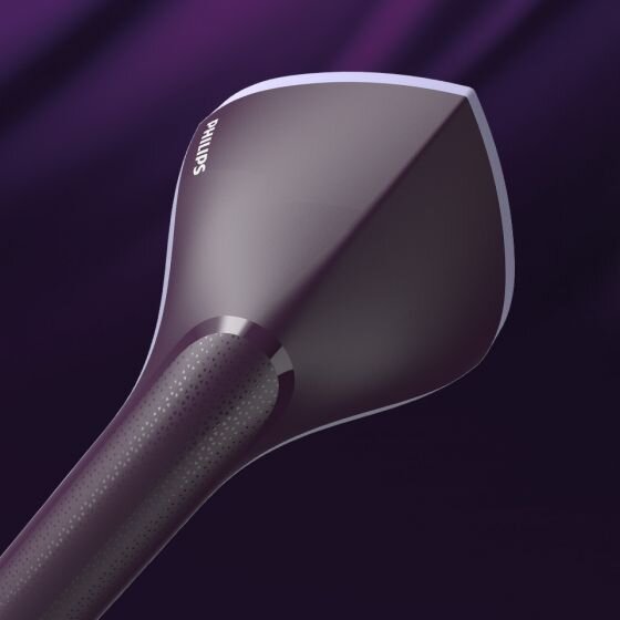 Na obrazie widoczna jest końcówka parownicy do ubrań w kolorze ciemnym z logo \'PHILIPS\'. Tło jest w odcieniach fioletu.