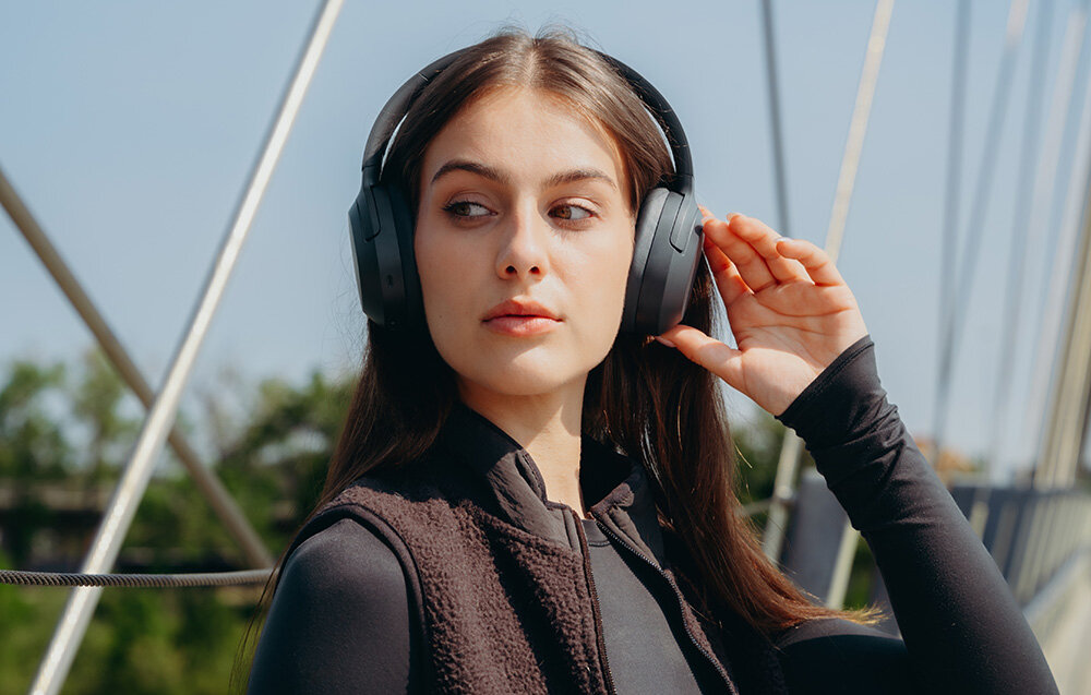 Edifier W820NB Plus V25 słuchawki bezprzewodowe ANC Bluetooth 6.1 LDAC Hi-Res Volume Guard Multipoint, osoba z założonymi słuchawkami nausznymi w plenerze