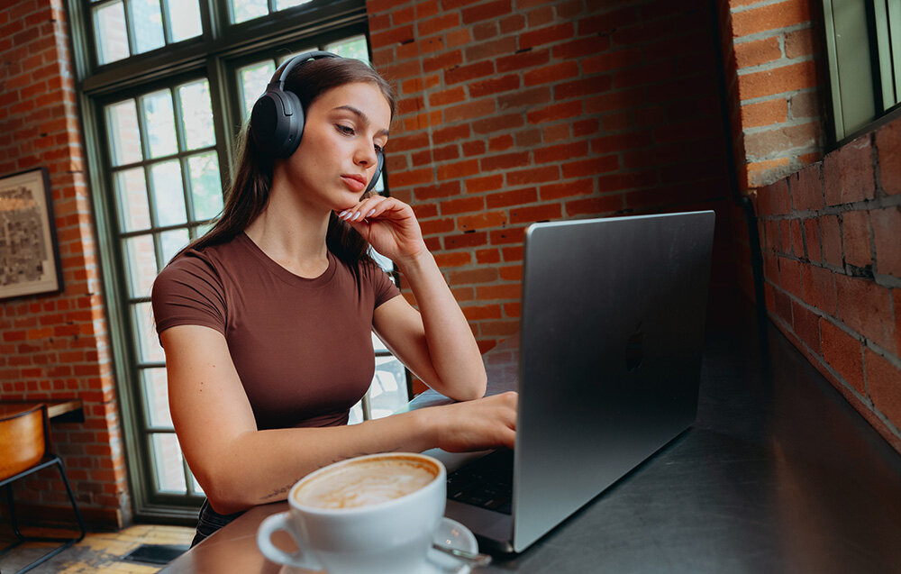 Edifier W820NB Plus V25 Bluetooth 6.1 Multipoint tryb Gaming niskie opóźnienie, osoba z założonymi słuchawkami nausznymi w pomieszczeniu