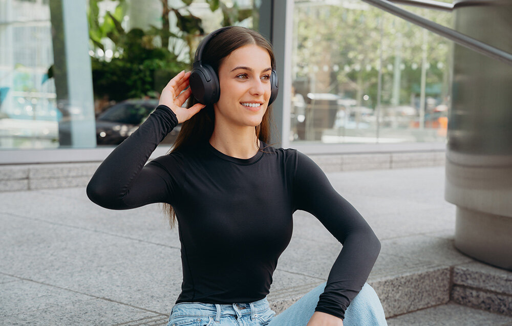 Edifier W820NB Plus V25 aplikacja ConneX Volume Guard przyciski diody sterowanie EQ, osoba z założonymi słuchawkami nausznymi w plenerze