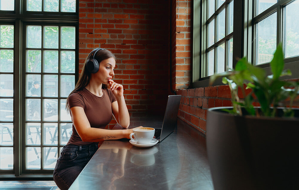 Edifier W820NB Plus V25 komfortowe lekkie słuchawki nauszne regulowany pałąk elegancki design, osoba z założonymi słuchawkami nausznymi w pomieszczeniu