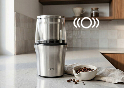 Młynek i rozdrabniacz 2w1 MMK-06M na kuchennym blacie, obok miska z ziarnami kawy i ikona koła z półkolami.