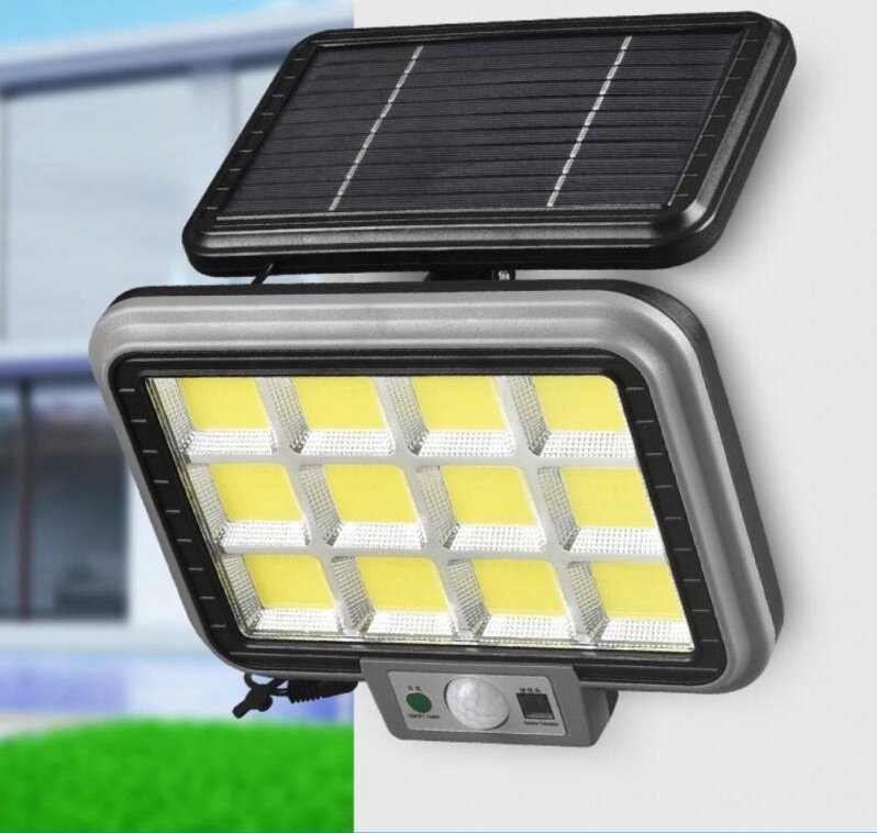 Na obrazie widoczna jest lampa solarna LED z panelem słonecznym na górze i czujnikiem ruchu oraz zmierzchu na dole. Lampa ma prostokątny kształt z kilkunastoma żółtymi diodami LED.