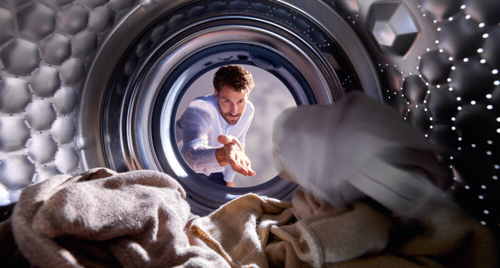 SUSZARKA MIELE TQ 1000 WP NOVA EDITION zdjęcie lifestyle mężczyzna wrzucanie ubrań do bębna wnętrze załadunek AddLoad dodawanie zapomnianego prania