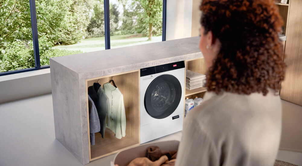 SUSZARKA MIELE TQ 1000 WP NOVA EDITION zdjęcie lifestyle kobieta zabudowa ubrania pralka front Czujnik zbliżeniowy MotionReact rozpoznanie ruchu zbliżenia aktywacja oświetlania wyświetlacza