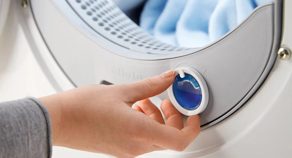 SUSZARKA MIELE TQ 1000 WP NOVA EDITION zdjęcie lifestyle kapsułka niebieski punkt dłoń System zapachowy FragranceDos kapsułki zapachowe różnorone zapachy wybór dla wrażliwej skóry