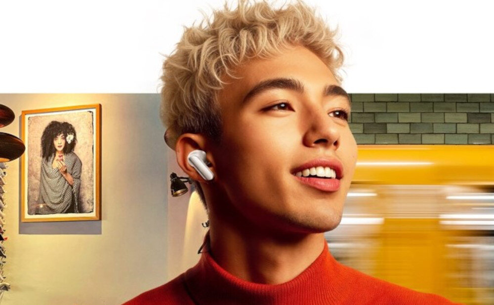 Słuchawki dokanałowe REALME Buds Air 7 Pro - Dostosowuje się do otoczenia, meżczyzna z założonymi słuchawkami dokanałowymi, w tle pokój oraz metro