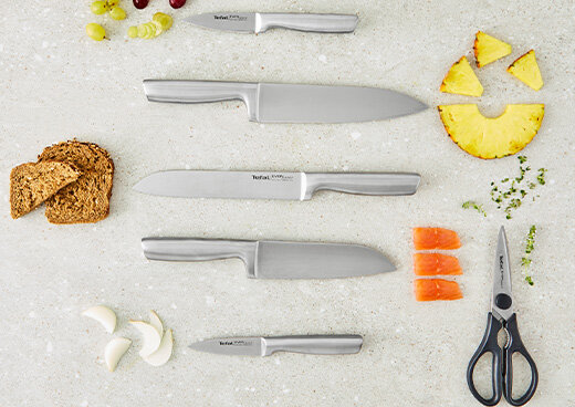 Zestaw noży kuchennych K2977S44 i nożyce kuchenne EverSharp ułożone na blacie z dodatkiem pokrojonych produktów spożywczych