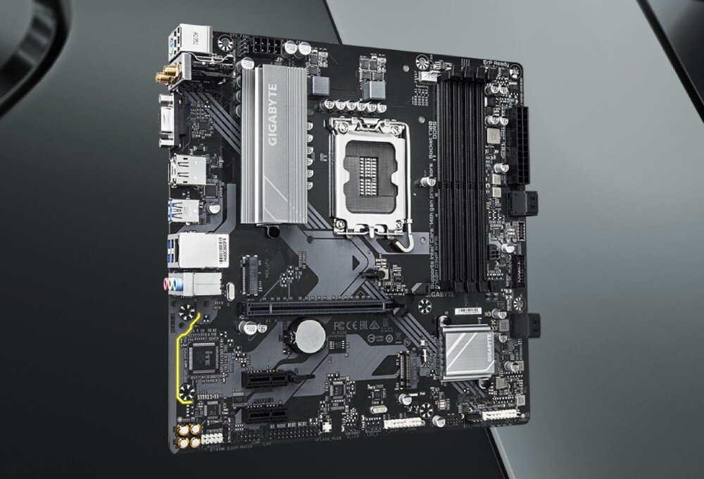 Komputer MAD DOG MD-I02WR32WP Płyta główna komputera z widocznymi gniazdami i srebrnymi radiatorami utrzymana w czarno-białej kolorystyce na szarym tle