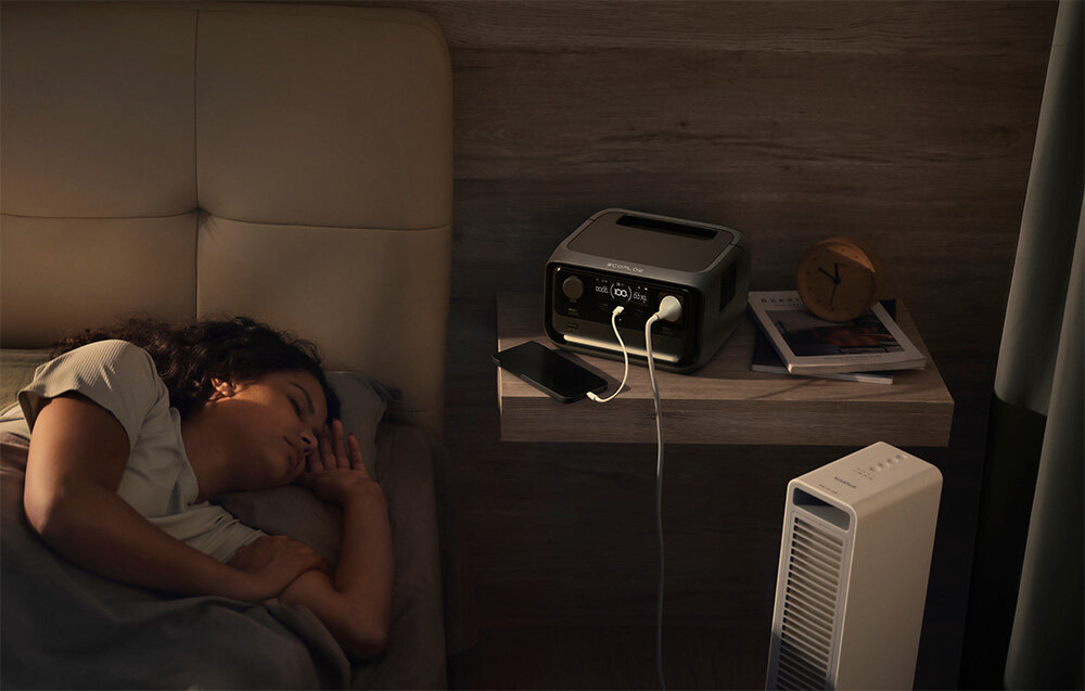 Stacja zasilania ECOFLOW River 3 Plus 286 Wh pokój osoba śpi w łóżku na stoliku nocnym stacja zasilania obok gazety telefon zaawansowany półprzewodnik GaN azotek galu GaN duża efektywność energetyczna dobre przewodnictwo minimalizuje ryzyko przegrzewania się urządzenia cicha praca poziom hałasu nie przekracza 30 dB