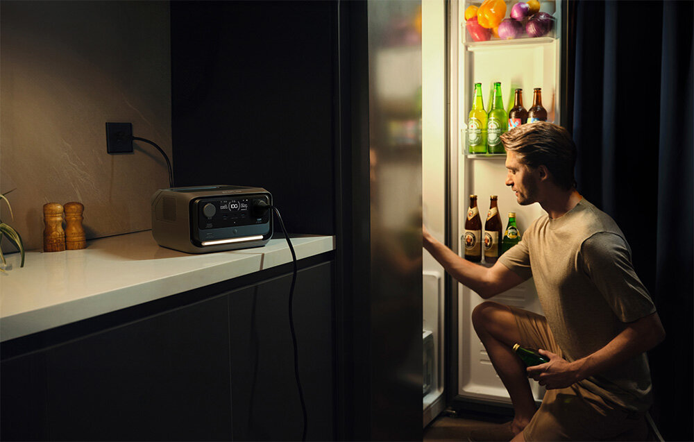 Stacja zasilania ECOFLOW River 3 Plus 286 Wh kuchnia stacja na blacie kuchennym obok mężczyzna klęka przed otwartą lodówką funkcja UPS zasilanie awaryjne tryb akumulatorowy w czasie poniżej 10 ms ciągłość zasilania w przypadku nagłych przerw w dostawie prądu ochrona przed utratą danych