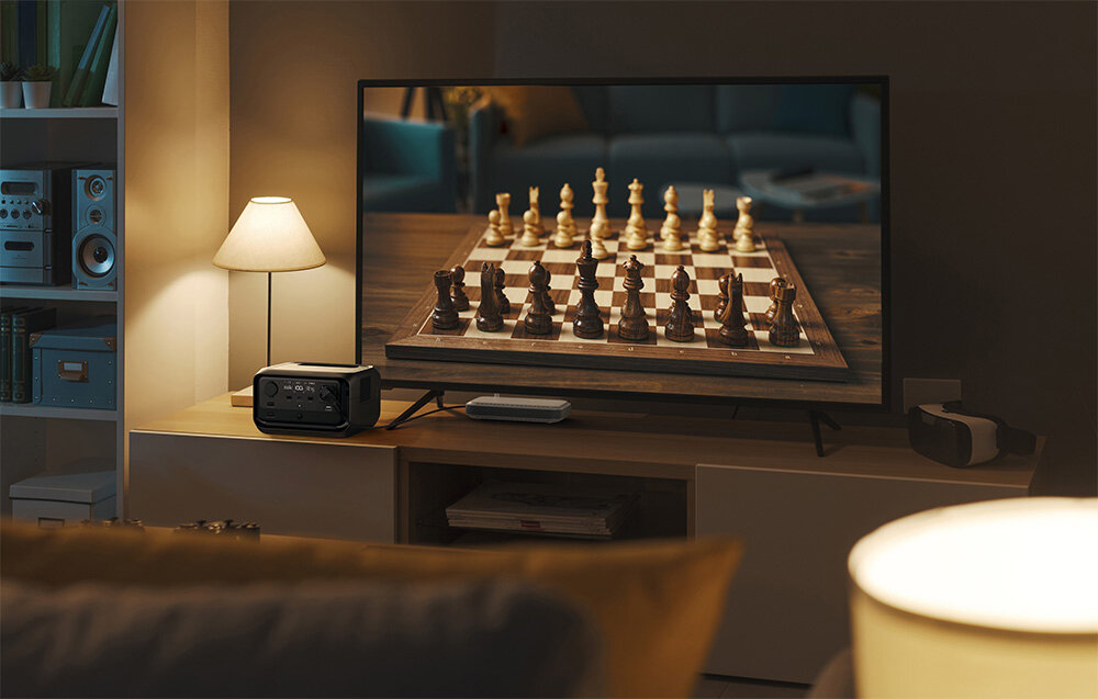 Stacja zasilania ECOFLOW River 3 Plus 286 Wh stacja na półce w pokoju obok telewizor i lampka ładowanie na cztery sposoby gniazdo AC czas ładowania około godziny gniazda samochodowego paneli fotowoltaicznych o mocy do 220 W lub generatora