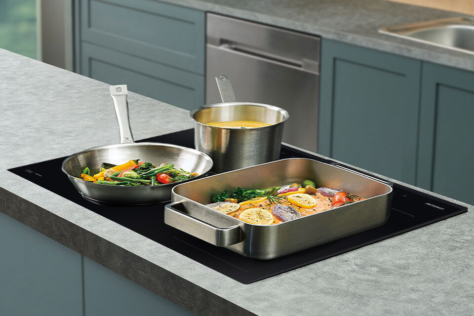 Metalowe naczynia widziane z boku na płycie indukcyjnej Samsung NZ85C5047GK 