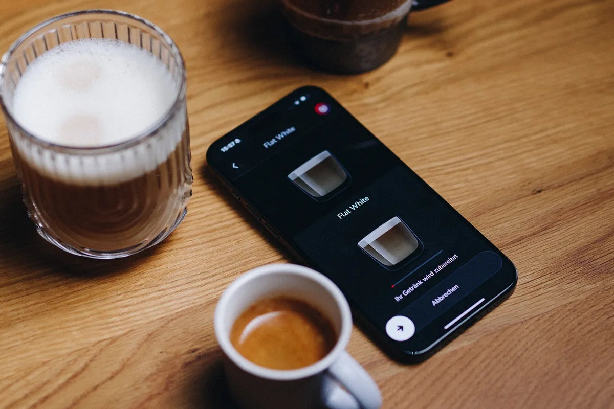 NIVONA Nivo 9101 - aplikacja mobilna na smartfonie obok kawy