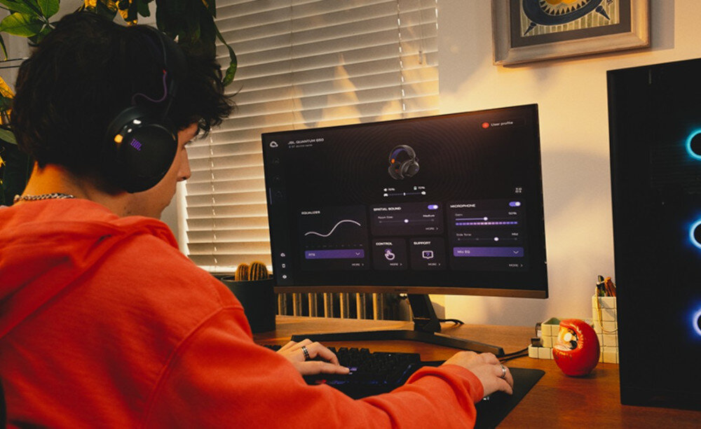 Słuchawki JBL Quantum 650 przetworniki 50 mm włókno węglowe mocny dźwięk, osoba siedząca w słuchawkach przy komputerze
