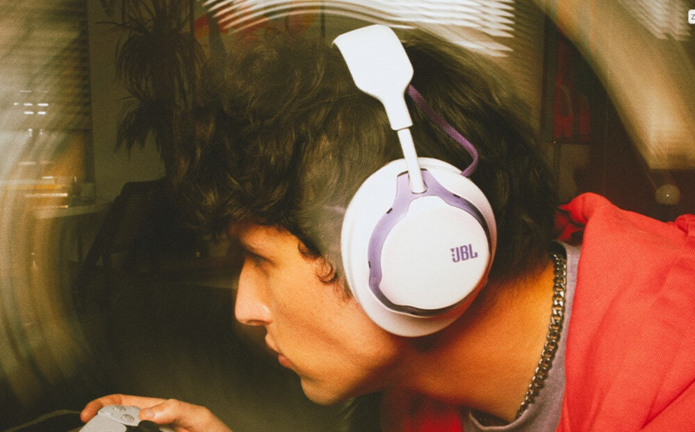 Słuchawki JBL Quantum 650 JBL Quantum Sound profil dźwięku gaming, osoba z załóżonymi słuchawkami z kontrolerem w rękach