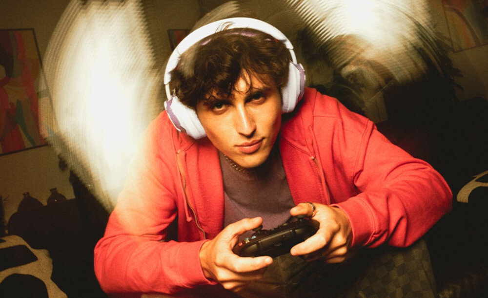 Słuchawki JBL Quantum 650 gamingowe dźwięk przestrzenny JBL Quantum Sound komfort, osoba z załóżonymi słuchawkami z kontrolerem w rękach