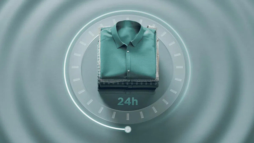 PRALKA TCL FP0834WA1PL Grafika przedstawia stos starannie złożonych ubrań umieszczony w centrum okrągłego zegara z podpisem „24h”, symbolizującego możliwość świeżego prania nawet po 24 godzinach od zakończenia cyklu harmonogram prania planowanie startu cyklu dopasowanie do trybu życia wygoda