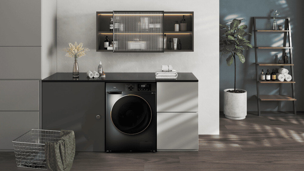PRALKO-SUSZARKA TCL CP1012SA0PL Ciemna pralka z dużymi drzwiami w miedzianej ramce wbudowana w zabudowę z czarnym blatem, otoczona dekoracyjną wiszącą szafką, rośliną w donicy, regałem z ręcznikami oraz metalowym koszem na pranie z zielonym ręcznikiem pranie i suszenie energooszczędność cicha praca higieniczne technologie wygoda oszczędność miejsca