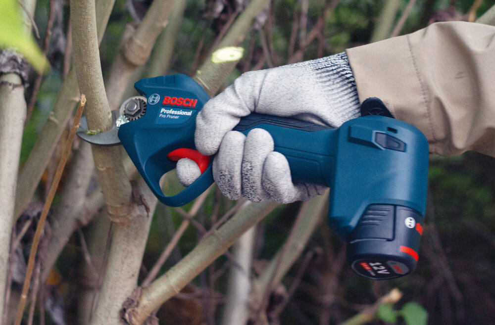 Sekator akumulatorowy BOSCH Pro Pruner 06019K1021 drzewo krzew osoba tnie gałęzie zbliżenie na akumulator akumulator litowo-jonowy 12 V o pojemności 3 Ah do 4500 cięć na jednym ładowaniu wskaźnik poziomu energii akumulator Li-ion nie wykazuje efektu pamięci w zestawie dwa akumulatory i ładowarka