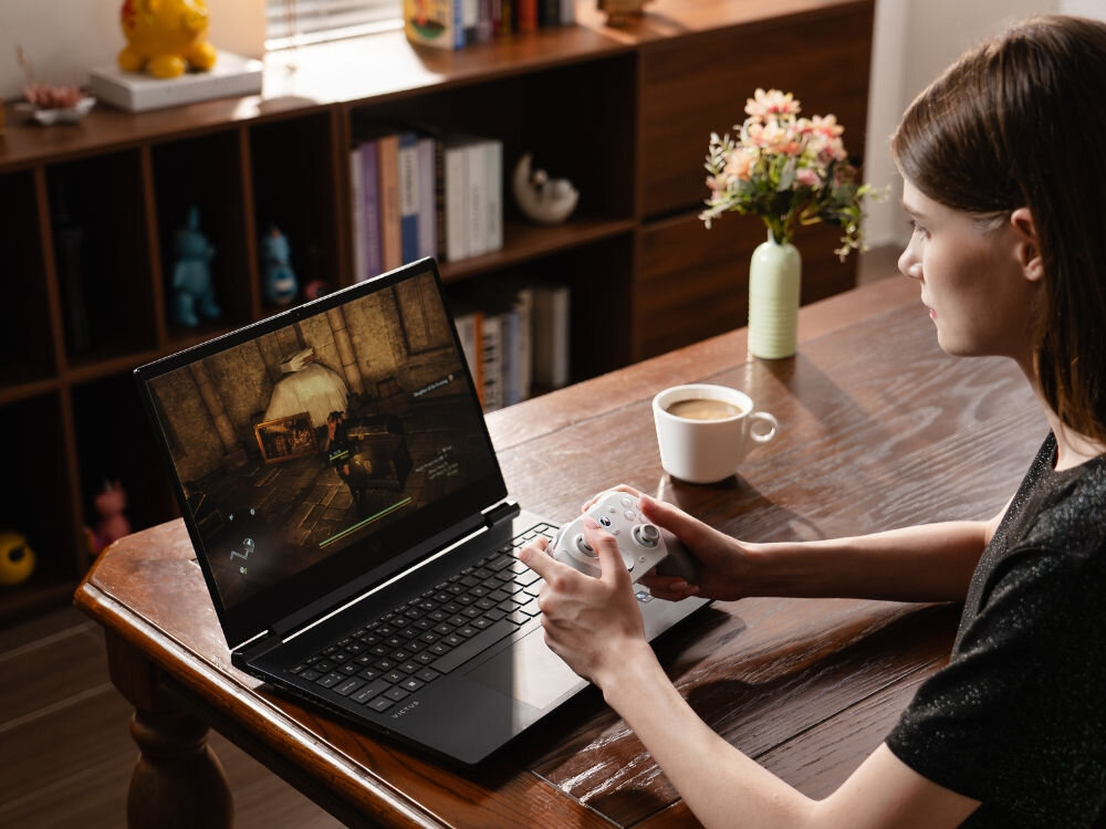 Kontroler GAMESIR G7 Pro Tri-Mode Czarny
                kobieta przy stole naprzeciwko laptopa z kontrolerem w ręku drążki mag-res tmr płynne ruchy odporność na dryf dokładne spusty hall effect hair trigger mode