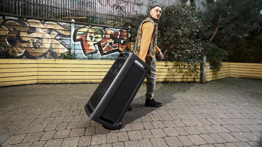 Power Audio SONY ULT Tower 9 AC Karaoke Czarny osoba ciągnąca głośnik na kółkach trzymając za uchwyt wytrzymałe kółka wbudowany uchwyt 