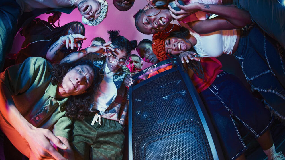 Power Audio SONY ULT Tower 9 AC Karaoke Czarny grupa osób na imprezie pochylona nad głośnikiem Sound Field Optimisation dostosowanie do otoczenia automatyczne dostosowanie dźwięku inteligentne strojenie