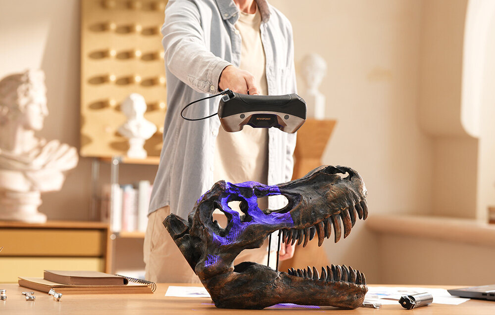 Zbliżenie na skaner 3D Revopoint MetroY Pro rzucający wzór niebieskich linii laserowych na skanowaną czaszkę dinozaura