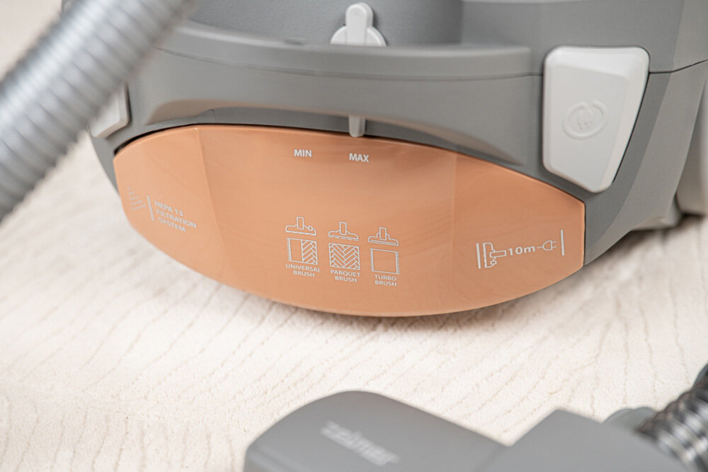 Fragment odkurzacza z widocznym panelem z oznaczeniami: MIN, MAX oraz symbolami szczotek: UNIVERSAL BRUSH, PARQUET BRUSH, TURBO BRUSH. Widoczny jest także symbol kabla z oznaczeniem 10m i logo ZELMER.