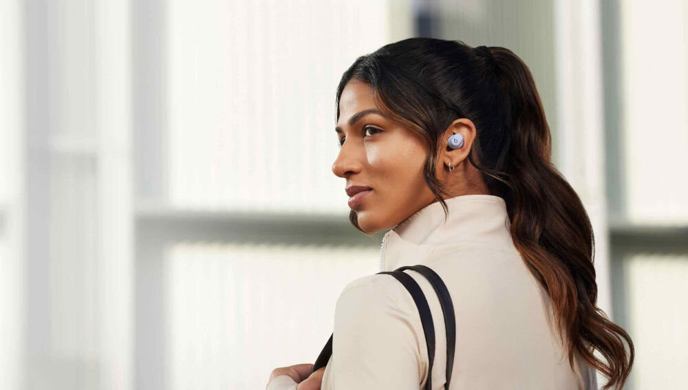 Słuchawki dokanałowe BEATS Solo Buds mikrofon redukcja szumów, czysty dźwięk rozmów, Bluetooth Class 1, osoba z założonymi słuchawkami dokanałowymi w płaszczu